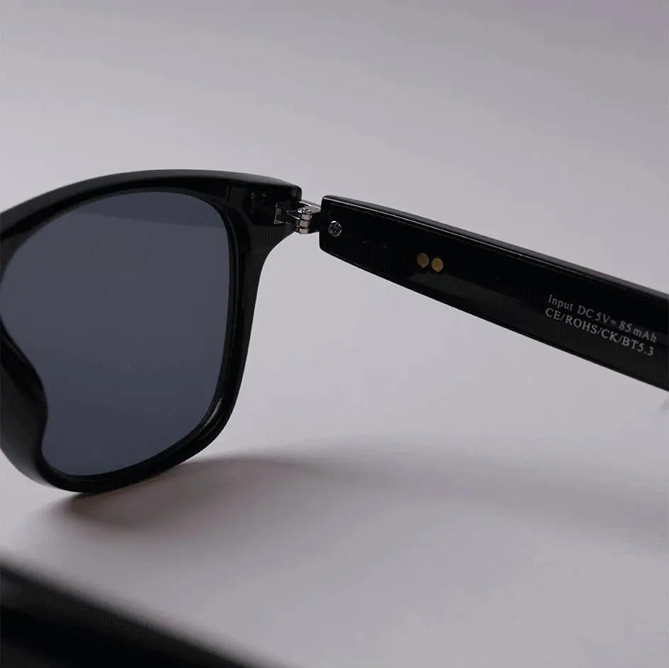 Close-up of DUSK Prime smart sunglasses showing built-in charging contact and arm hinge detail