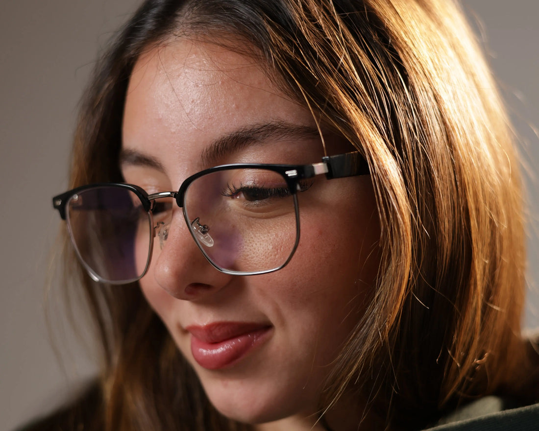 Close-up of a woman smiling while wearing DUSK Halo smart blue light glasses with clear lenses and black frame