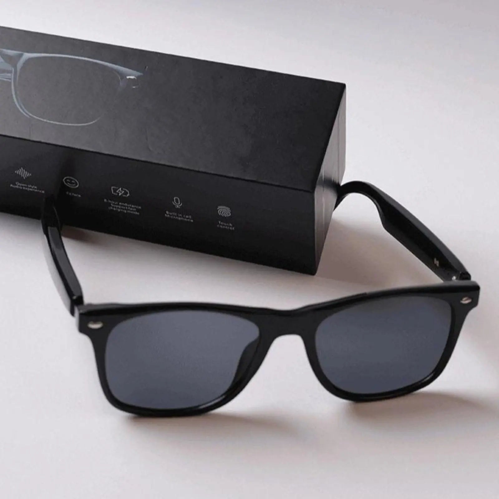 DUSK Prime smart sunglasses with black polarized lenses placed beside branded packaging box